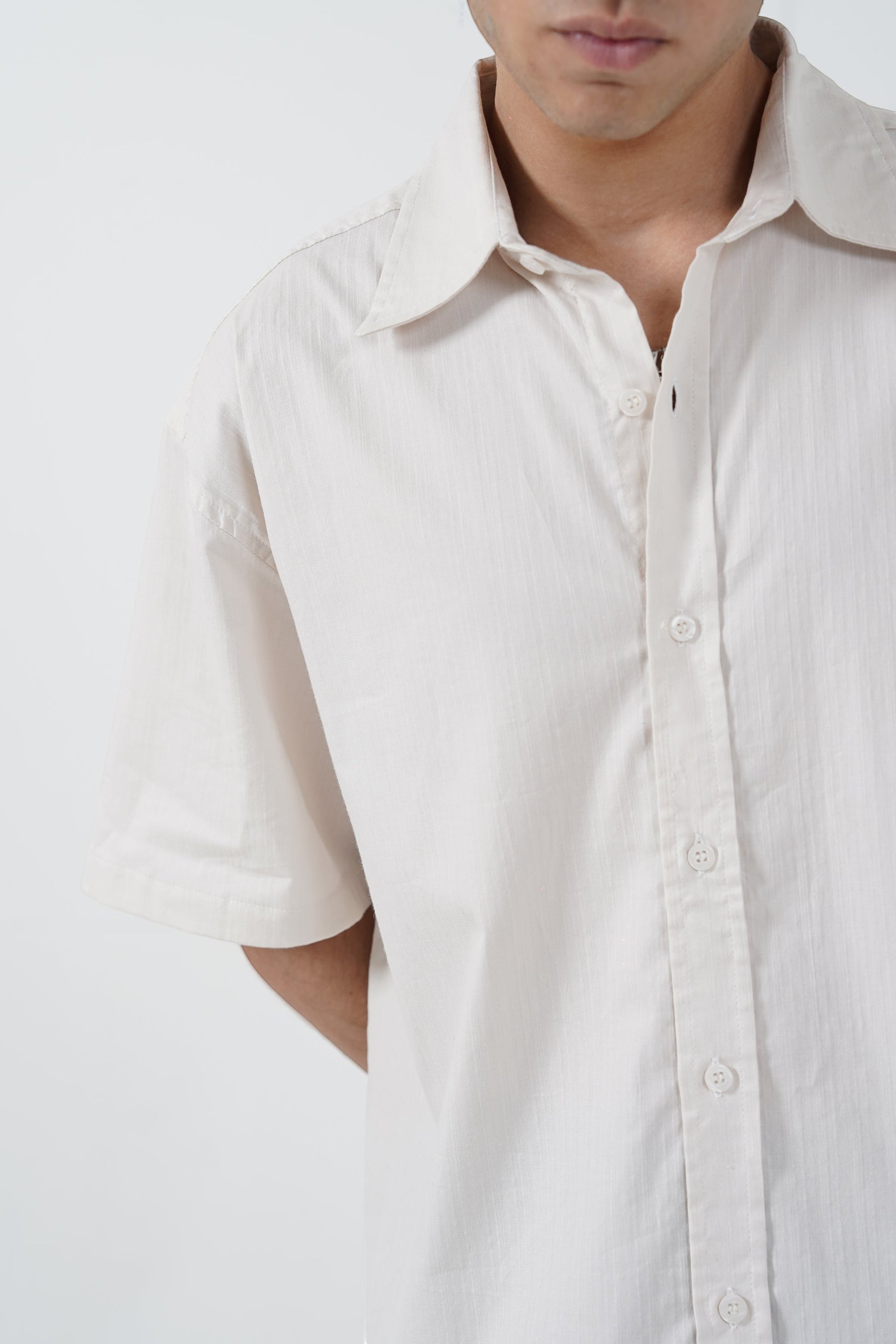 RAA-AY unisex off-white 100% cotton boxy fit bowler shirt with subtle textured pattern on shoulders and vertical stripes.